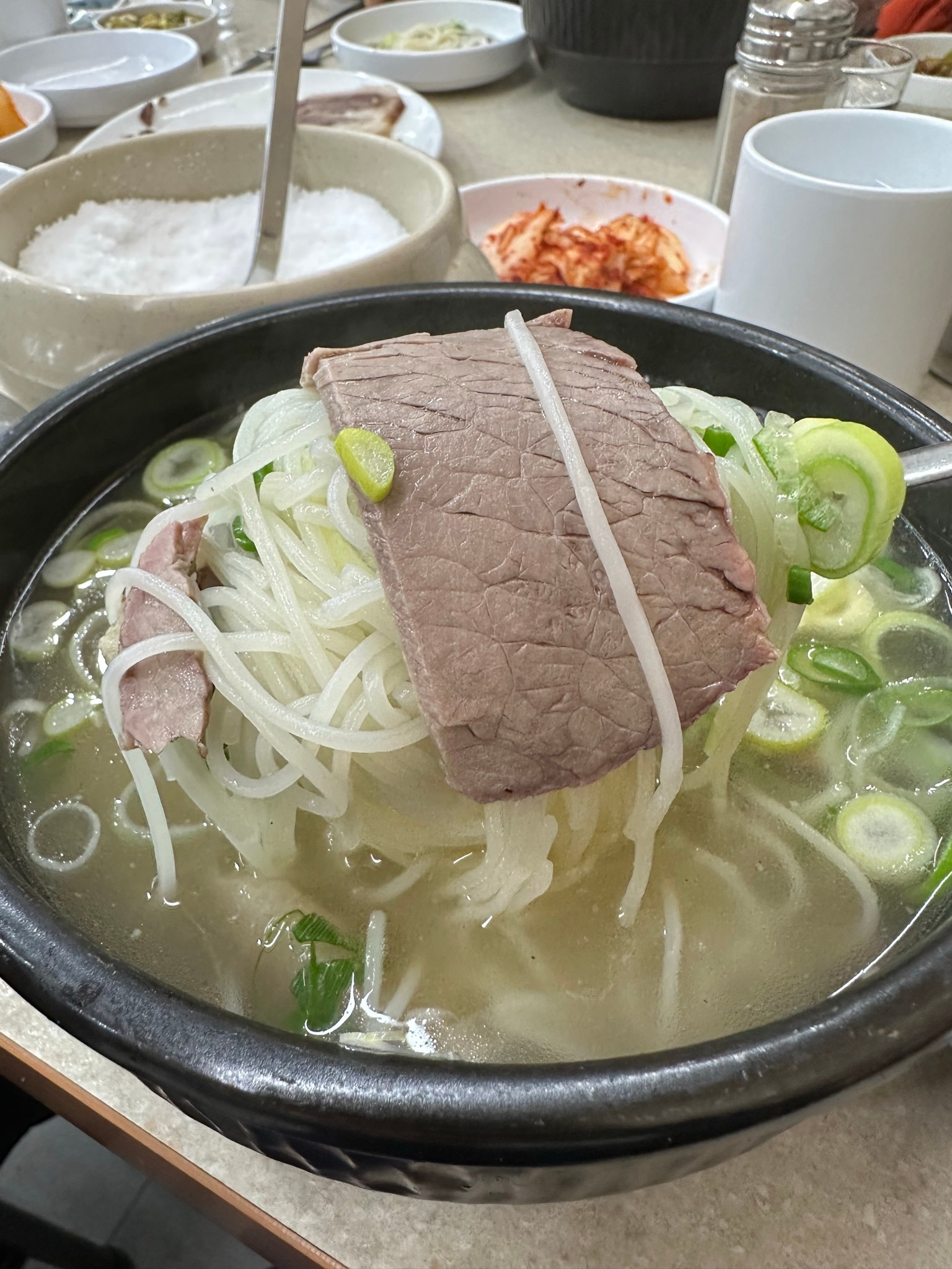 소면과 소고기가 올라온 숟가락, 대파를 더한 국물