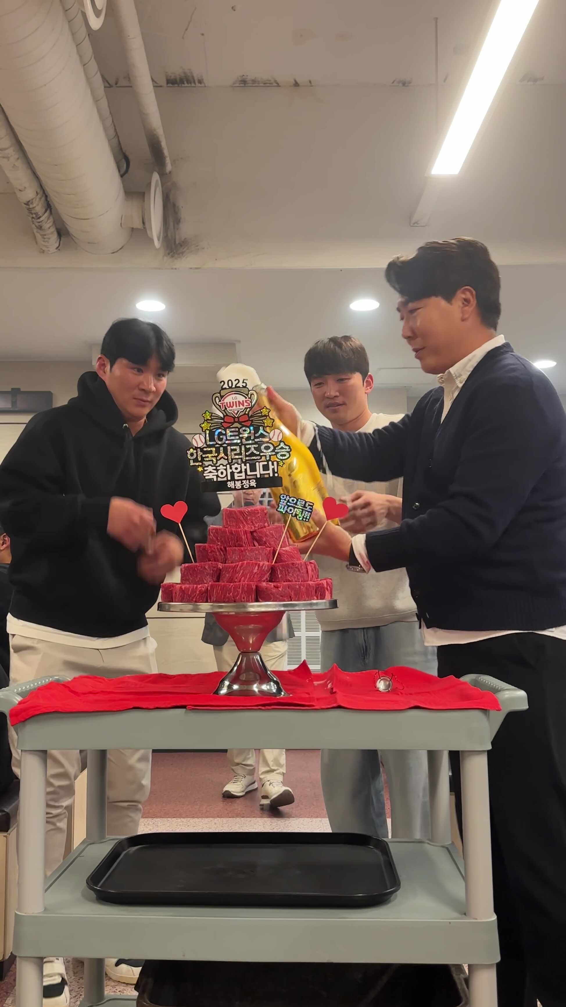 해봉정육 본점의 2025 통합우승 축하 회식에서 안심 고기 케이크와 샴페인을 앞에 두고 함께 축하하는 오지환·박해민 선수